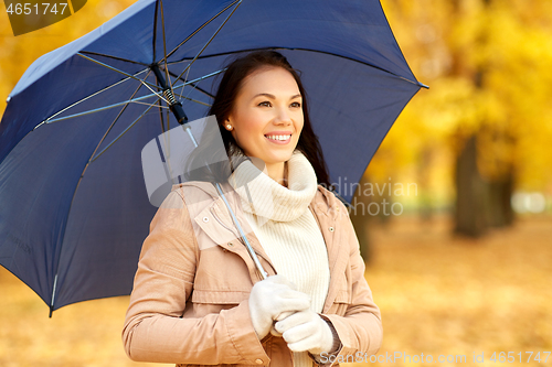 Image of happy woman with umbrella in autumn park