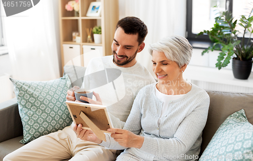 Image of adult son and senior mother with photo at home