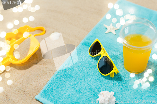 Image of sunglasses, sand toys and juice on beach towel