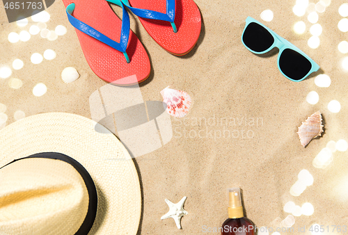 Image of straw hat, flip flops and sunglasses on beach sand