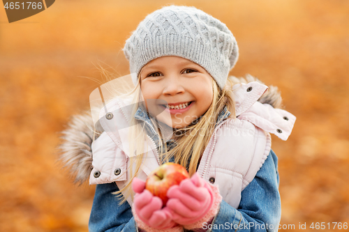 Image of portrait of happy little girl with apple in autumn