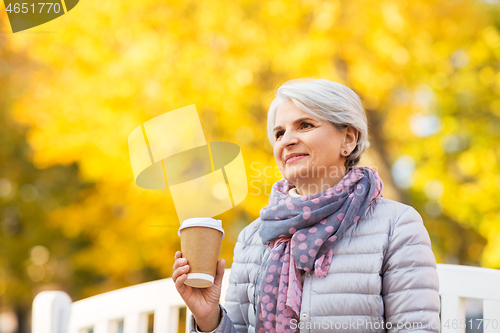 Image of senior woman drinking coffee in autumn park