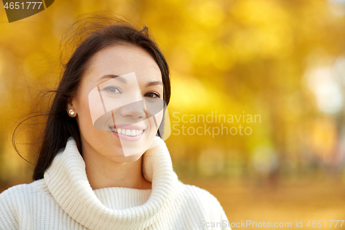 Image of portrait of happy young woman in autumn park