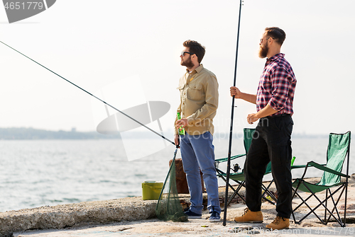 Image of male friends with fishing rods and beer on pier