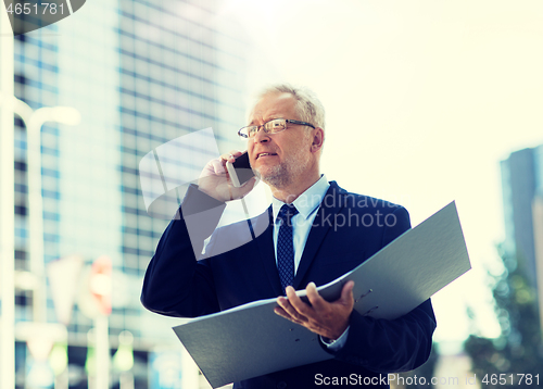 Image of senior businessman calling on smartphone in city