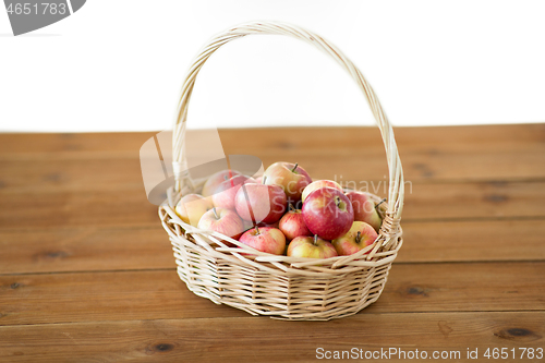 Image of ripe apples in wicker basket on wooden table