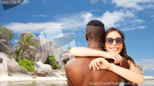 Image of happy mixed race couple hugging on summer beach