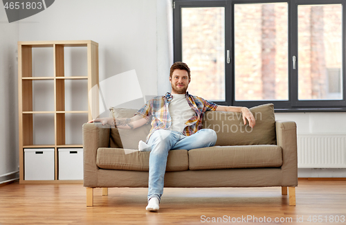 Image of happy man sitting on sofa at new home