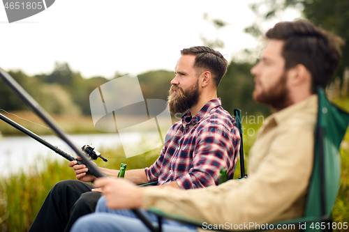 Image of friends with fishing rods at lake or river