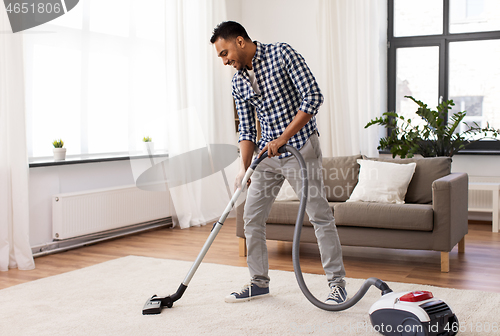 Image of indian man with vacuum cleaner at home