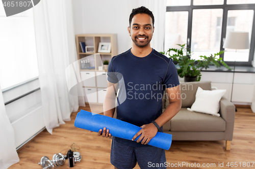 Image of smiling indian man with exercise mat at home