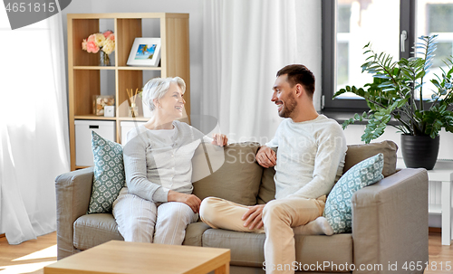 Image of senior mother talking to adult son at home