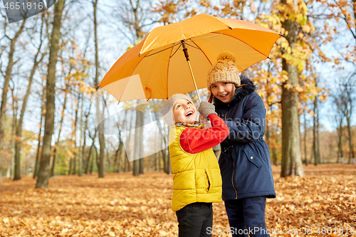 Image of happy children with umbrella at autumn park