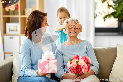 Image of mother and daughter greeting grandmother at home