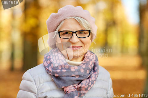 Image of portrait of happy senior woman at autumn park