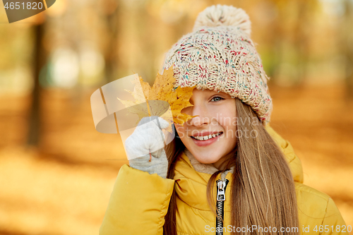 Image of portrait of girl with maple leaf at autumn park