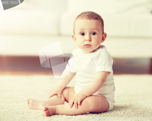 Image of happy baby boy or girl sitting on floor at home