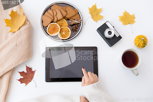 Image of hands with tablet pc, tea and autumn leaves