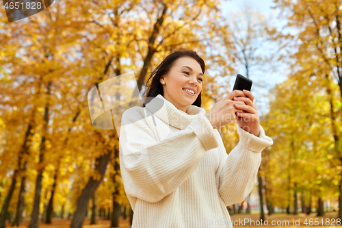 Image of woman with smartphone in autumn park