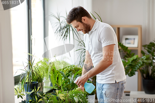 Image of man spraying houseplants with water at home