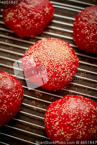 Image of Fresh baked red homemade burger buns with sesame top view. Placed on metal grill.