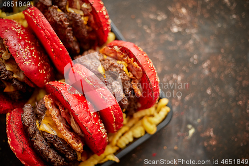 Image of Set of four homemade giant double becon cheese burgers. Served with french fries on wooden board.