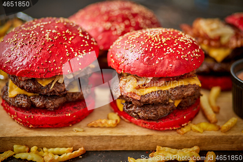 Image of Set of four homemade giant double becon cheese burgers. Served with french fries on wooden board.