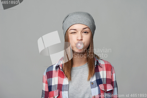 Image of Smiling teen girl blowing bubblegum winking at you