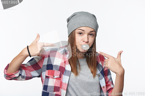 Image of Closeup of cheeky teen girl blowing bubblegum and pointing at it