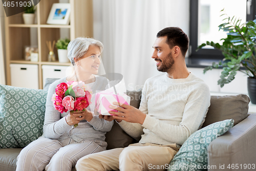 Image of son giving present and flowers to senior mother