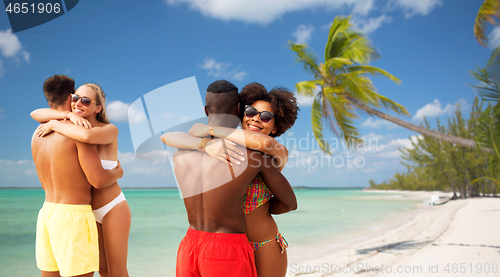 Image of happy friends or couples hugging on summer beach