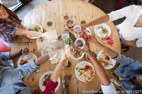 Image of friends eating and clinking glasses at restaurant