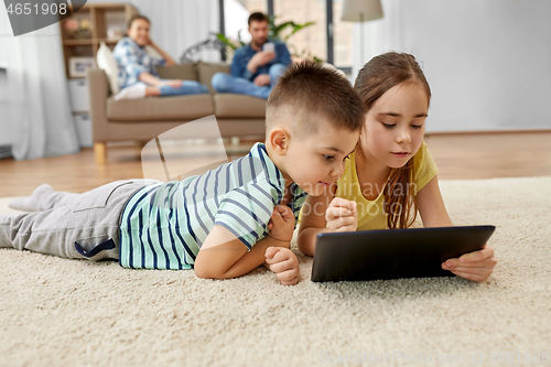 Image of brother and sister with tablet computer at home