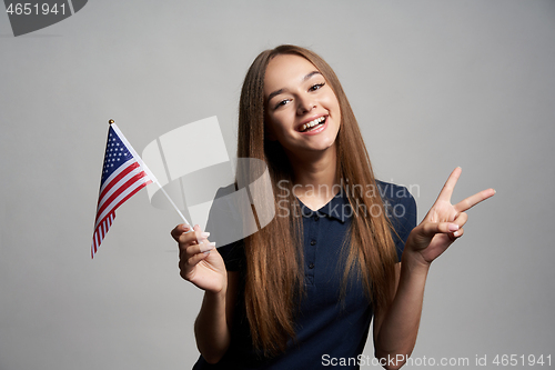 Image of Happy female holding USA flag and gesturing Victory