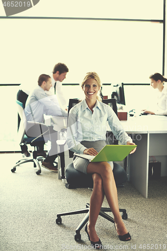 Image of business woman with her staff in background at office