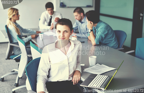 Image of business woman with her staff in background at office