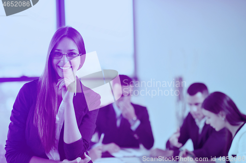 Image of business woman with her staff in background at office