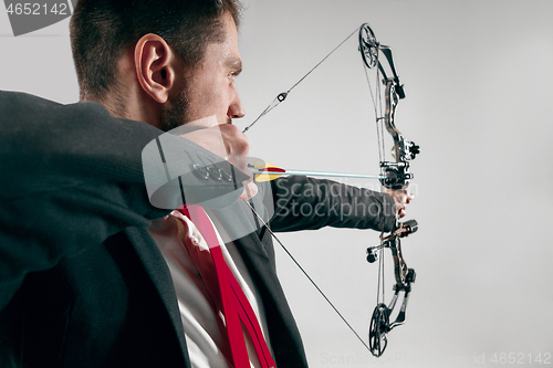 Image of Businessman aiming at target with bow and arrow, isolated on white background