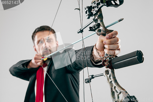 Image of Businessman aiming at target with bow and arrow, isolated on white background