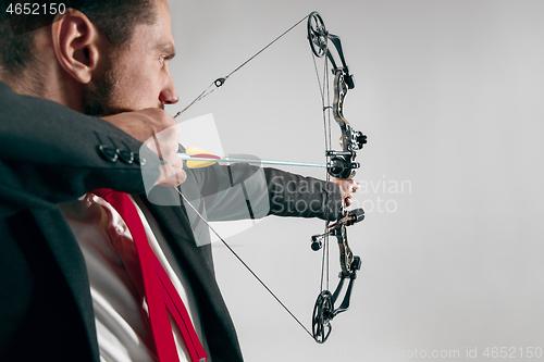 Image of Businessman aiming at target with bow and arrow, isolated on white background