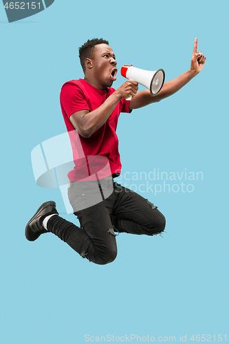 Image of Soccer fan jumping on blue background. The young afro man as football fan with megaphone