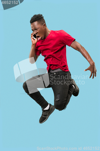 Image of always on mobile. Full length of handsome young man taking phone while jumping