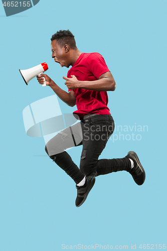 Image of Soccer fan jumping on blue background. The young afro man as football fan with megaphone