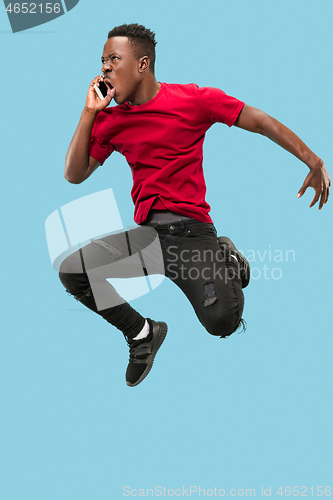 Image of always on mobile. Full length of handsome young man taking phone while jumping