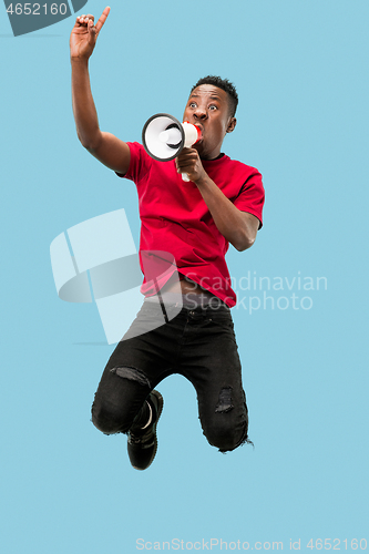 Image of Soccer fan jumping on blue background. The young afro man as football fan with megaphone