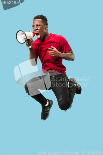 Image of Soccer fan jumping on blue background. The young afro man as football fan with megaphone