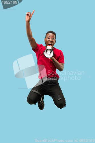 Image of Soccer fan jumping on blue background. The young afro man as football fan with megaphone