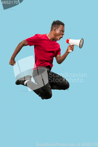 Image of Soccer fan jumping on blue background. The young afro man as football fan with megaphone