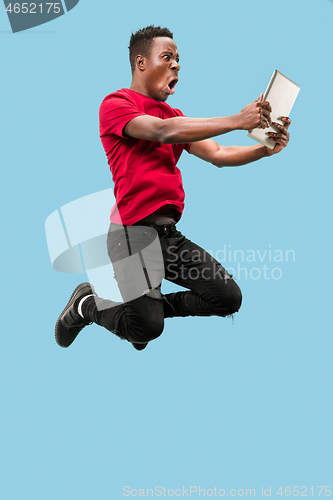 Image of Image of happy excited young african man jumping isolated over yellow background using laptop