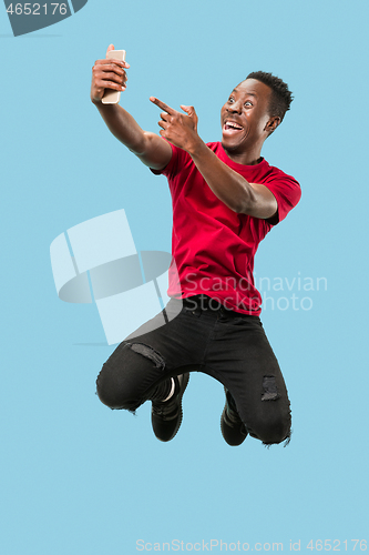 Image of always on mobile. Full length of handsome young man taking phone while jumping